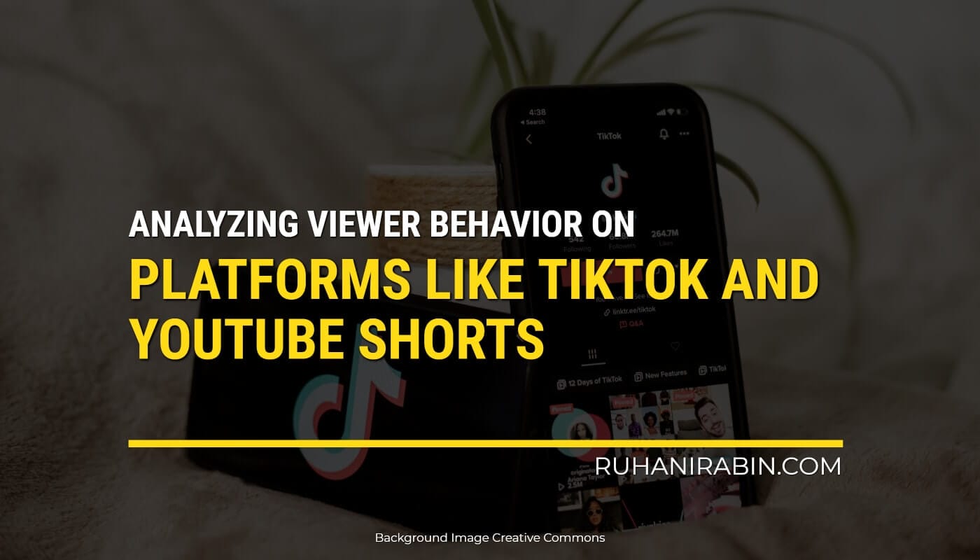 A picture of a smartphone showing the TikTok app screen, sitting on a table with a plant in the background. There's text on the image that says: "Studying behavior on platforms like TikTok and YouTube Shorts" credited to "www.ruhanirabin.com.