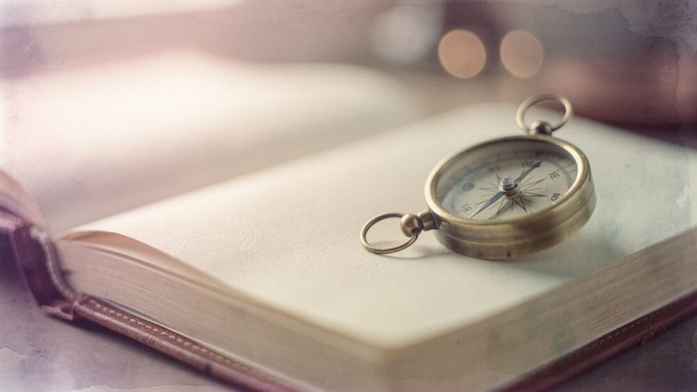 Compass resting on an open book, symbolizing guidance for AI citation optimized web content.