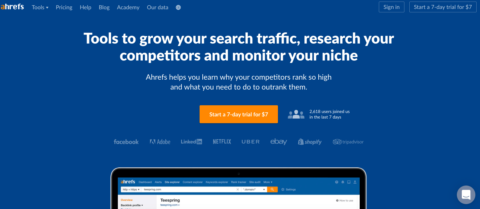 The homepage of the Ahrefs website shows a headline about resources to boost search traffic and analyze competitors in digital marketing. There is also a button for a trial offer and logos of different companies. You can see part of a laptop screen showcasing the platform's interface.