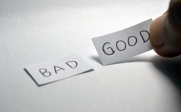 A close-up picture shows two small pieces of paper on a table. The one on the left says "BAD" in black ink, and the one on the right, being held by someone's hand, says "GOOD." The word "GOOD" is highlighted to represent an important choice in deciding whether to build or buy for a business.