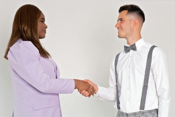 A black woman and a caucasian man exchange a professional handshake, symbolizing successful business collaboration.